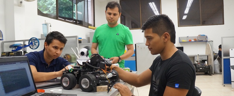 Imagen estudiantes de robótica revisando un vehículo con ruedas en Unibagué