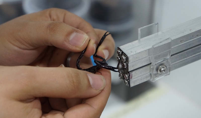 Primer plano de un par de manos doblando unos cables para el micrositio de investigaciones en Unibagué